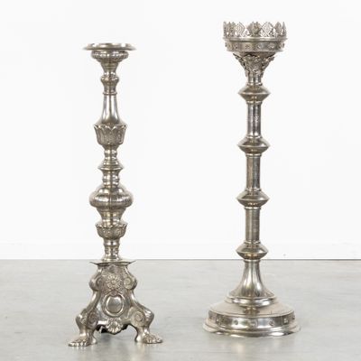 pair of silver candlesticks on a table with a white wall in the background
