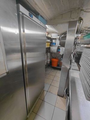 un grand réfrigérateur en acier inoxydable dans une cuisine au sol carrelé