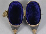 pair of blue velvet covered shoes with gold accents on a white surface