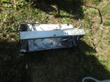 a broken microwave sitting in the grass next to a chair