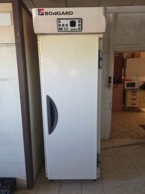 un réfrigérateur blanc qui se trouve dans une pièce au sol carrelé