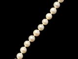un collier de perles avec un fermoir en or sur fond noir