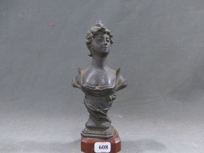 un buste en bronze représentant une femme, posé sur un socle en bois