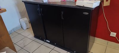 un petit réfrigérateur noir dans un coin de la pièce