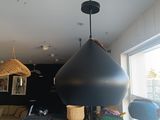 une grande lampe noire suspendue au plafond dans une pièce