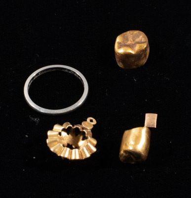 two gold rings and a silver ring on a black surface