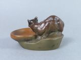 a statue of a cat that is sitting on top of a bowl
