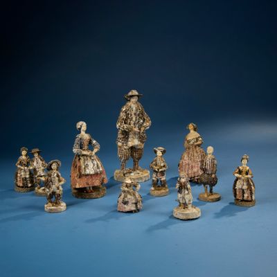 plusieurs figurines représentant des personnes vêtues de costumes d'époque et coiffées de chapeaux d'époque
