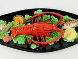 une assiette sur laquelle se trouvent un homard et d'autres mets