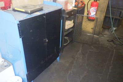 une armoire bleue avec une porte noire et une borne d'incendie rouge en arrière-plan