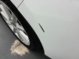 a close up of a white car with a hole in the side of it