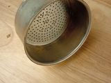 a metal strainer sitting on a wooden table