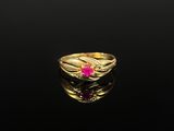 un gros plan d'une bague en or avec une pierre rose au centre