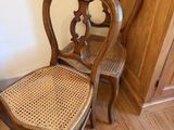 une paire de chaises anciennes françaises à dossier en rotin, dans un coin d'une pièce
