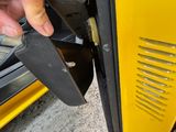 a person holding a knife near the door of a yellow bus