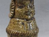 a small ceramic vase with a face on it