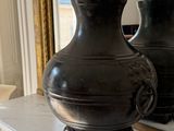 two black vases sitting on top of a mantle