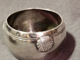 a silver bowl with a shell on it on a table