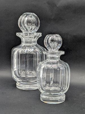 two clear glass bottles sitting next to each other on a black surface