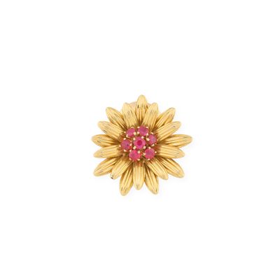 a close up of a yellow flower brooch with a pink center