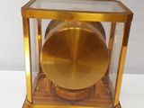 a gold clock in a glass case on a white table