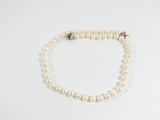 un collier de perles blanches avec un fermoir en argent sur fond blanc
