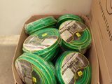 a cardboard box filled with green hoses on the floor