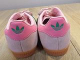 pink and green adidas sneakers on a wooden surface