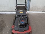an image of a lawn mower parked in front of a garage
