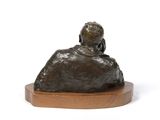 statue of a woman sitting on a rock on a wooden base