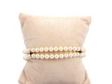 pearl bracelets on a pillow on a white background