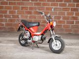 a small red motorcycle parked in front of a brick wall