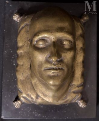 a gold sculpture of a woman ' s face on a black surface