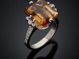 an orange sapphire and diamond ring on a black surface