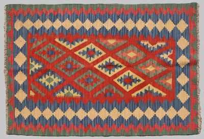 un tapis rouge, bleu et vert orné d'un motif en losanges