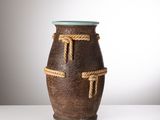 un vase marron entouré d'une corde, posé sur une table blanche