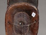 an image of a wooden mask on a stand with a tag on it