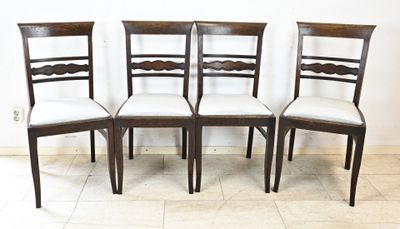 quatre chaises en bois aux assises rembourrées de blanc sont disposées sur un sol carrelé