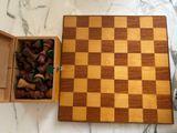 a wooden box with chess pieces in it on a marble table