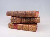 three old books stacked on top of each other on a white surface