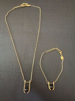 a gold necklace and bracelet set with a black stone