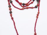 beaded necklace with red beads and a cross on a white background