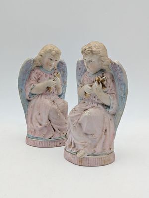 deux figurines d'anges assis l'un à côté de l'autre sur une surface blanche