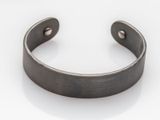gros plan d'un bracelet métallique sur une surface blanche