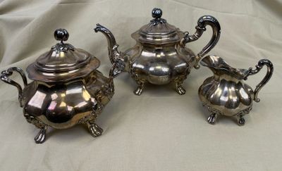 trois théières en argent posées sur une nappe blanche