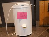 a white trash can sitting on the floor with a pink sticker on it