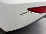 the rear end of a white car with scratches on it