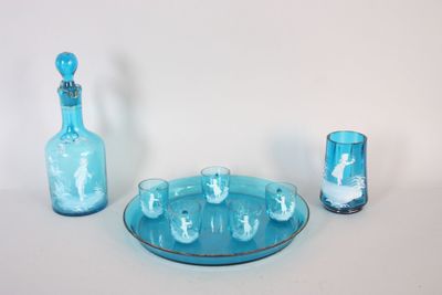 une assiette bleue sur laquelle sont posés une bouteille et un verre