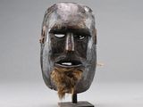 un gros plan d'un masque en bois barbu posé sur un socle