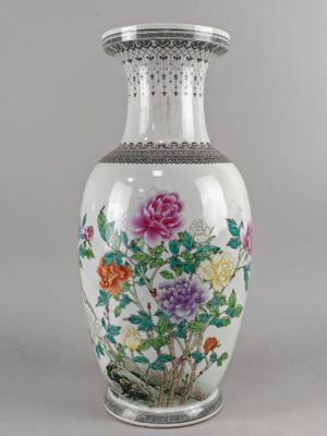 un vase avec des fleurs peintes dessus, posé sur une table